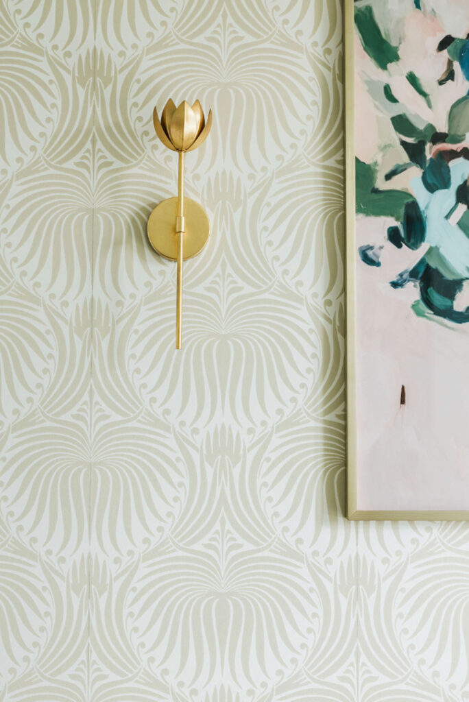 Brass wall sconce on soft geometric wallpaper, paired with a framed abstract artwork.