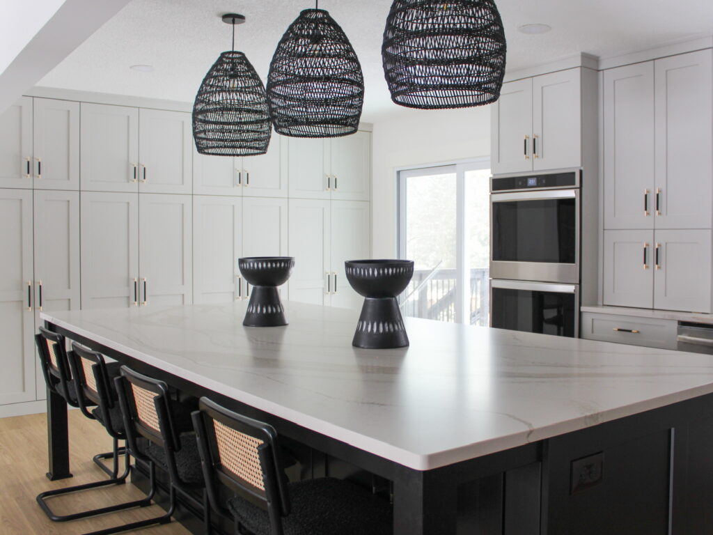 Modern kitchen in the Minneapolis-St. Paul's suburbs showcase a marble-look island, matte black stools, and floor-to-ceiling soft white cabinetry.
