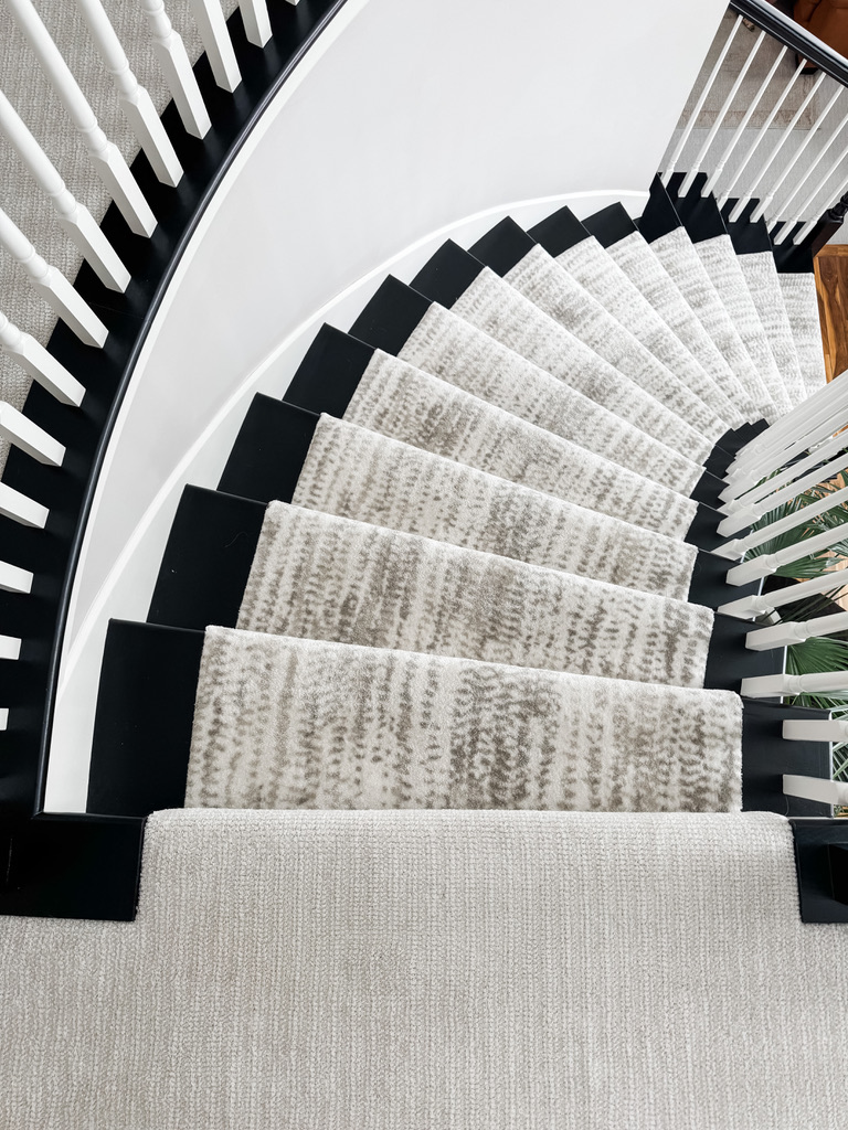 Curved staircase with white spindles and black railings featuring a modern patterned carpet runner in a Minneapolis-St. Paul home.