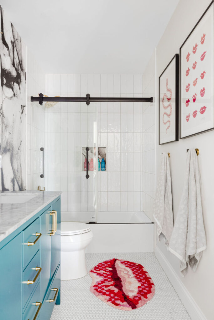 Double vanity with teal cabinets, marble top, and black-framed mirrors against bold black-and-white wall art in a Minneapolis-St. Paul area remodeled home. The boutique interior design team at Firelight Style House brought artistic flair and personalized color choices to create a statement-making bathroom remodel.