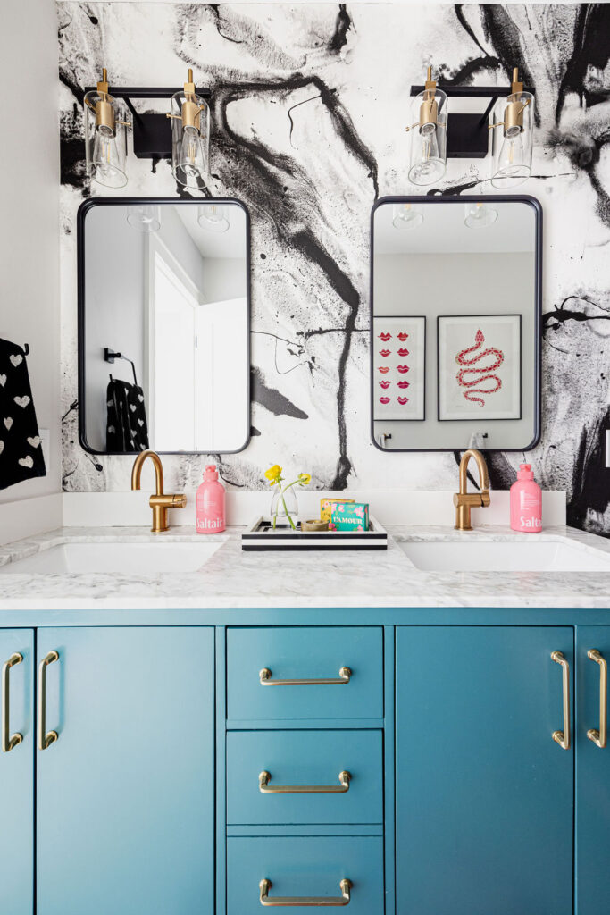 Double vanity with teal cabinets, marble top, and black-framed mirrors against bold black-and-white wall art in a Minneapolis-St. Paul area home. The boutique interior design team brought artistic flair and personalized color choices to create a statement-making bathroom remodel.