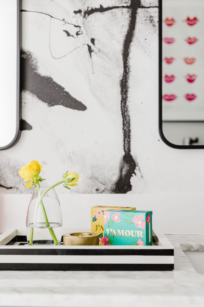 Close-up of a vanity tray with yellow flowers and colorful soap boxes on a marble countertop in a remodeled Minneapolis-St. Paul bathroom.