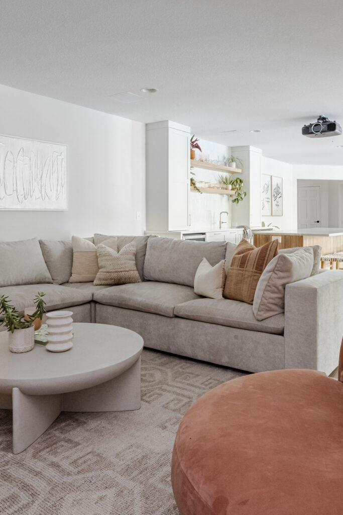 Bright, modern living space with a light sectional, beige woven rug and cream coffee table creating a clean, airy feel.