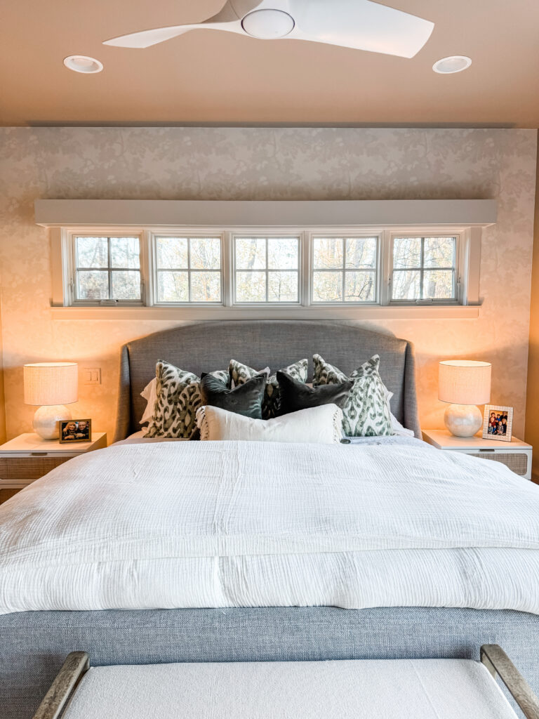 master bedroom with a grey bed frame, green throw pillows and two night stands with lamps.