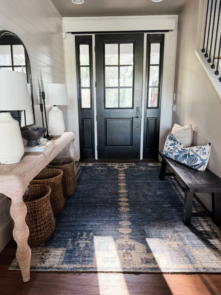 Entryway with a console table, bench and blue oriental rug.