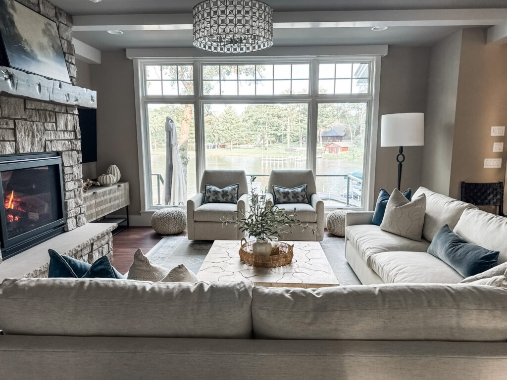 A large sectional with two accent chairs in front of a large window and fireplace.