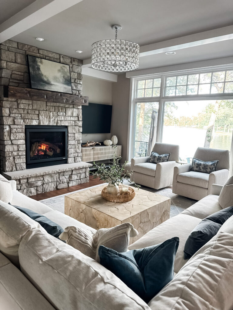A large sectional with two accent chairs in front of a large window and fireplace.